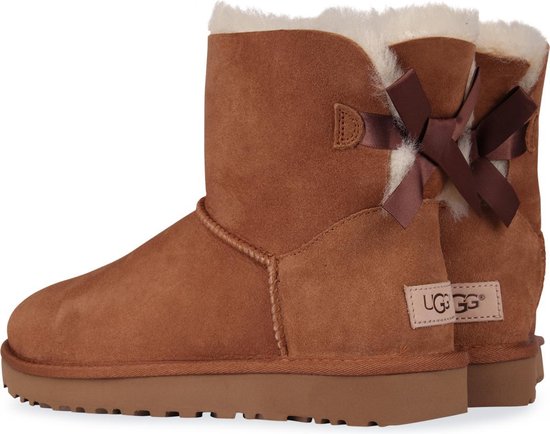Cognackleurige suède enkellaarsjes met witte vachtvoering en dubbele strikken op de hielen. UGG logo op de hiel.