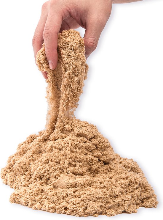 Een hand die goudkleurig zand vasthoudt en het uit een zandkasteel laat vallen. Goudkleurig zand.