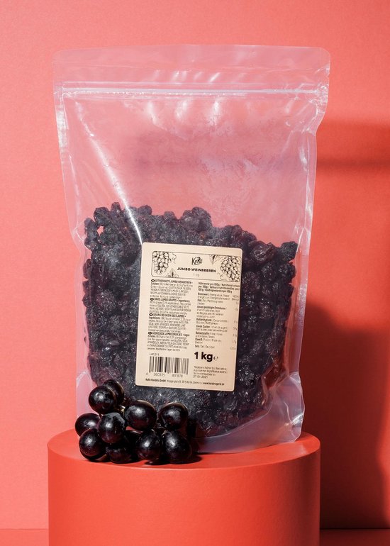 Een 1 kg zak jumbo krenten wordt op een rode cilinder getoond met een tros druiven.