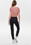 Zwarte chino broek met hoge taille gedragen door een model in een roze t-shirt en witte sneakers.