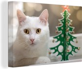 Canvas Schilderij Witte kat ligt naast een papieren kerstboom - 120x80 cm - Wanddecoratie
