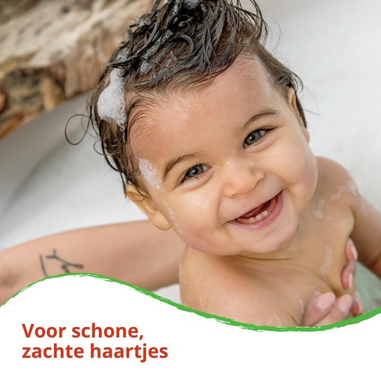 Een lachende baby in bad met sop op het haar. Tekst: Voor schone, zachte haartjes.