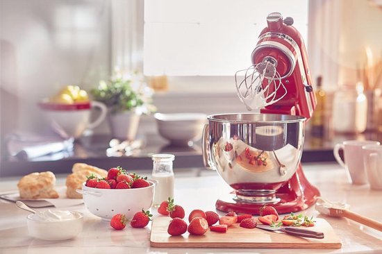 Robot pâtissier KitchenAid Artisan rouge Empire en cours d'utilisation, avec de la crème dans le bol argenté.