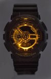 Zwart G-Shock horloge met een gloeiende gouden wijzerplaat en digitale tijdweergave.