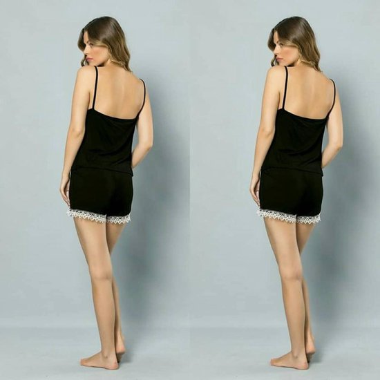 Zijzicht van een model dat een zwarte pyjamaset draagt met witte kanten afwerking aan de shorts.