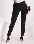 Zwarte broek met hoge taille, gedragen door een model met zwarte pumps en een tasje.