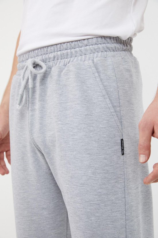 Detail van de tailleband en zak van een grijze joggingbroek.
