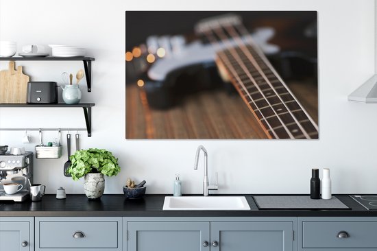 Une guitare basse repose sur une table Toile 140x90 cm - Tirage photo sur toile (Décoration murale salon / chambre)