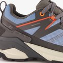 Detail van de zijkant van een blauw-grijze wandelschoen met oranje accenten en de tekst "WATERPROOF".