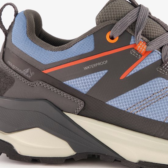 Detail van de zijkant van een blauw-grijze wandelschoen met oranje accenten en de tekst "WATERPROOF".