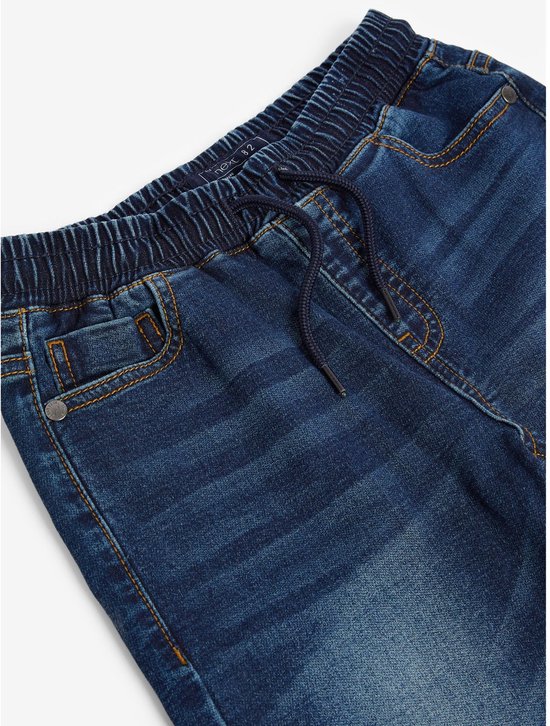 Detail van de elastische tailleband en het trekkoord van een donkerblauwe jeans.