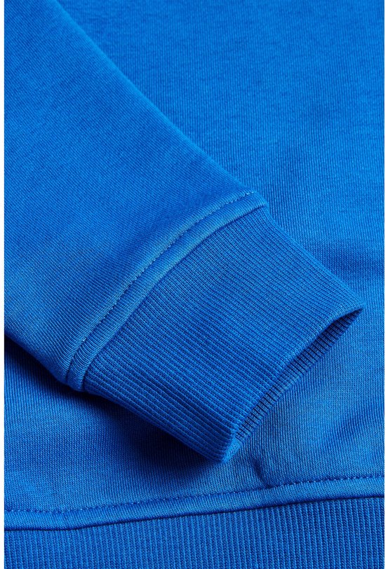 Detail van de geribbelde manchetten van een blauwe trui.