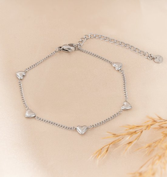 Zilverkleurige armband met kleine hartjes aan een fijne schakelketting, sluiting met verlengketting.
