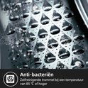 Gros plan du tambour de lave-linge avec des gouttelettes d'eau sur la surface en acier inoxydable, avec le texte 'Anti-bactérien'.