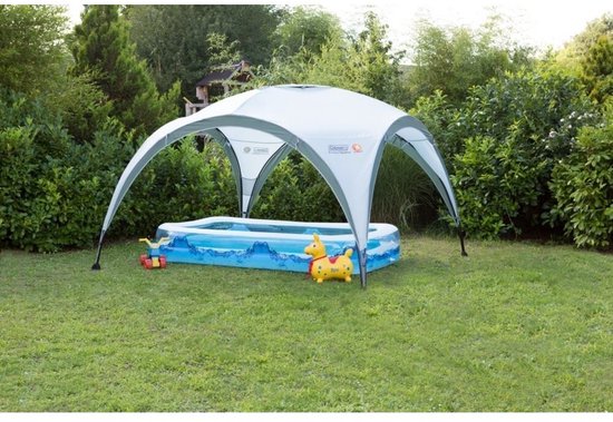 Een Coleman partytent boven een opblaasbaar zwembad in de tuin.
