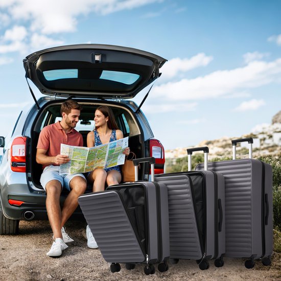 Een stel dat op een auto zit met de kofferbak open, drie grijze koffers op de grond.