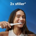 Vrouw met bruin haar lacht en poetst tanden met beige Oral-B iO; claim '2x stiller'.