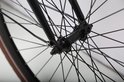 Zwart fietswiel met veel spaken, zwarte velg en bruine band.