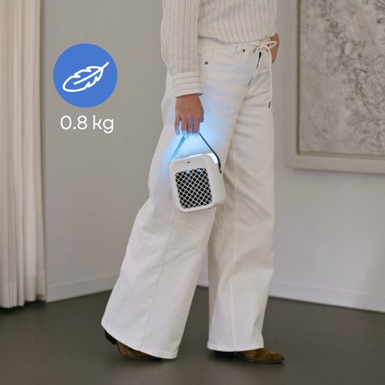 Een persoon in witte broek en gestreepte blouse houdt een lichtgewicht, wit en grijs airco-apparaatje vast met een blauwe gloed.