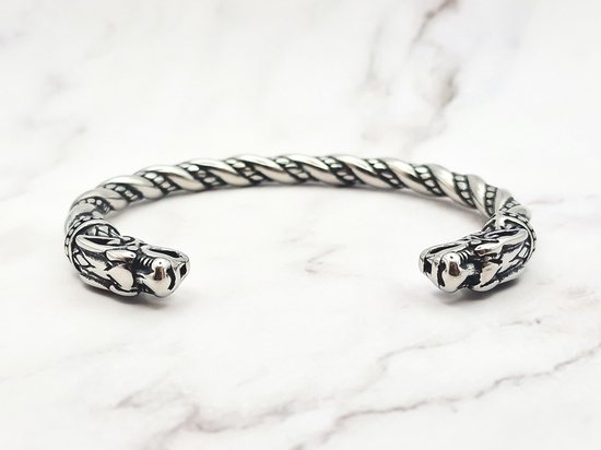 Zilverkleurige, gedraaide armband met drakenkopuiteinden op een marmeren achtergrond.