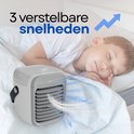 Wit en grijs mobiel airco-apparaat met 3 snelheden, naast een slapend kind in bed.