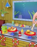 Mini Krabby Patty-burgers, ketchup en mosterd op rode tafels met een 'Now Serving'-bord, macarons en een flesje met een brief.
