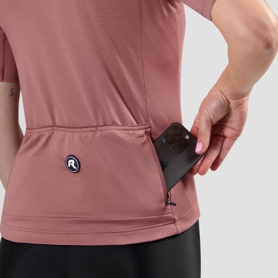 Gedetailleerde achterkant van een roze damesfietsshirt dat een smartphone in de zak opbergt.