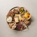 Borrelplank met kaas, worst, olijven, crackers, chips, dipsaus en grissini.