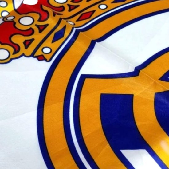Close-up van het Real Madrid logo met kroon, gouden en blauwe lijnen op wit.