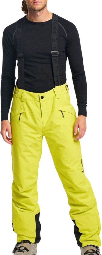 Homme portant une manche longue noire, un pantalon de ski jaune vif avec bretelles et des chaussures de ski brunes. Logo Tenson sur la jambe du pantalon.