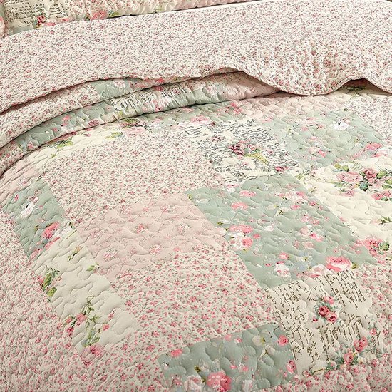 Gedetailleerde close-up van een patchwork sprei met roze bloemen, groene en roze patronen en tekst.