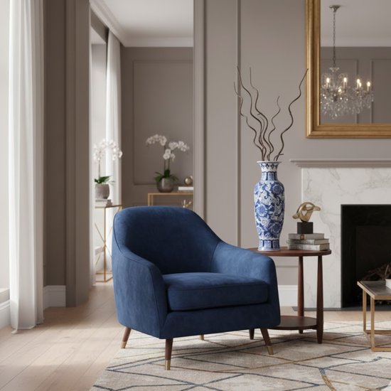Een stoffen fauteuil in de kleur nachtblauw, met houten poten, in een woonkamer naast een tafel met een blauw-witte vaas