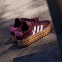Bordeauxrode Adidas sneakers met witte strepen, bruine zool en roze accenten.