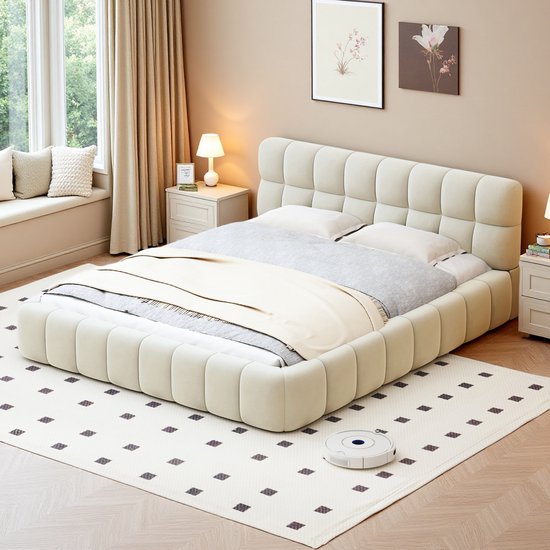 Gestoffeerd tweepersoonsbed in beige, met een laag, bolvormig frame en een vierkant gepoft hoofdeinde.