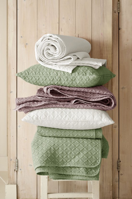 Pile de linge de lit dans des couleurs pastel: blanc, vert et rose. Matières douces avec un motif tissé.