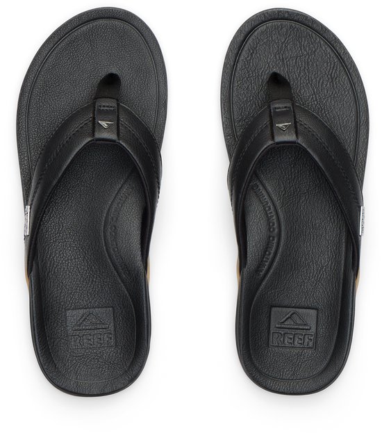 Paar zwarte Reef teenslippers van leer met bruine zolen.