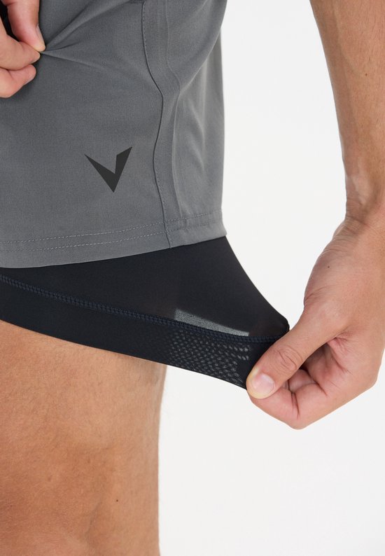 Close-up van de onderkant van een grijze sportshort met zwart binnenbroekje met mesh-structuur.