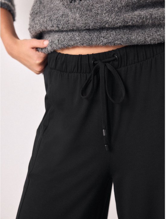 Detail van de tailleband van een zwarte joggingbroek met trekkoord.