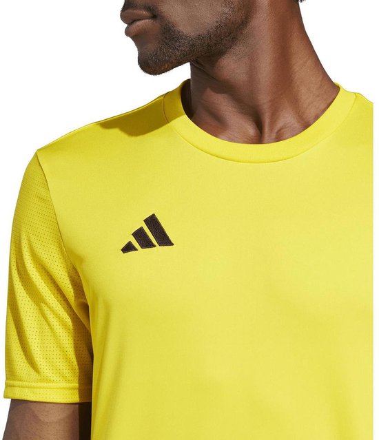 Close-up van de linkerschouder en borst van een geel Adidas sportshirt met zwart Adidas logo.