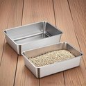 Twee roestvrijstalen bakken op een houten vloer, één gevuld met kattengritkorrels.