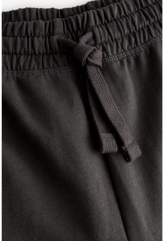 Close-up van de tailleband en het trekkoord van een donkergrijze joggingbroek.