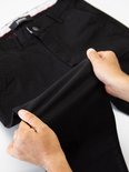 Mannenhanden die een zwarte, slappe chinobroek van Yazubi oprollen.