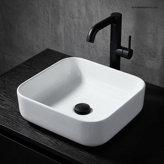 Witte vierkante wastafel met zwarte kraan op een donker meubel.