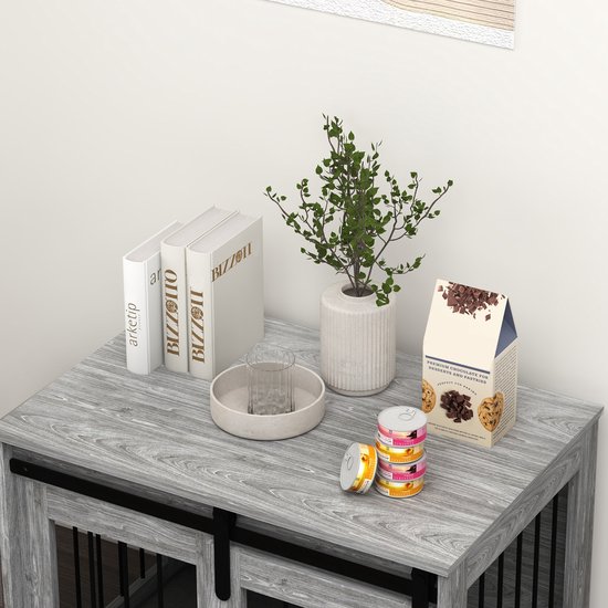 Grijze hondenbench met schuifdeuren en zwarte spijlen, op een houten vloer.