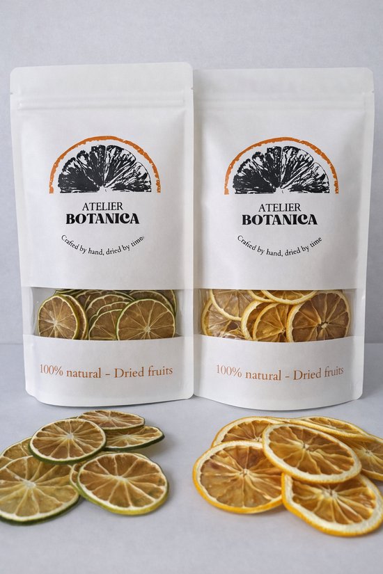 Twee verpakkingen Atelier Botanica met gedroogde limoen- en sinaasappelschijfjes. Ook losse schijfjes zichtbaar.