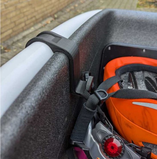 Zwarte plastic houder bevestigd aan de rand van een bakfiets, met een helm met oranje accenten.