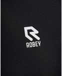 Close-up van het witte Robey logo op een zwarte poloshirt.