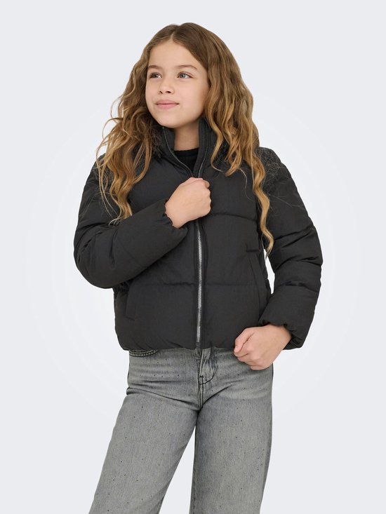 Meisje met lang blond haar draagt een zwarte pufferjas en wijde grijze jeans.