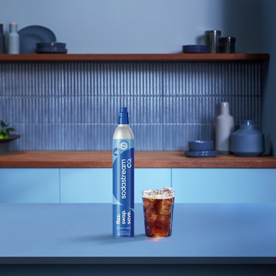 Sodastream CO2-cilinder van 60L in een keukenomgeving naast een glas bruisend water met ijs.