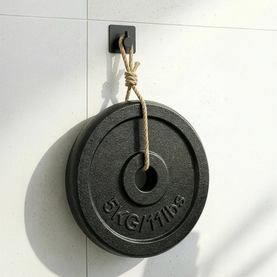 Een zwarte haak van Minismus hangt een halterschijf van 5 kg aan een tegelmuur.